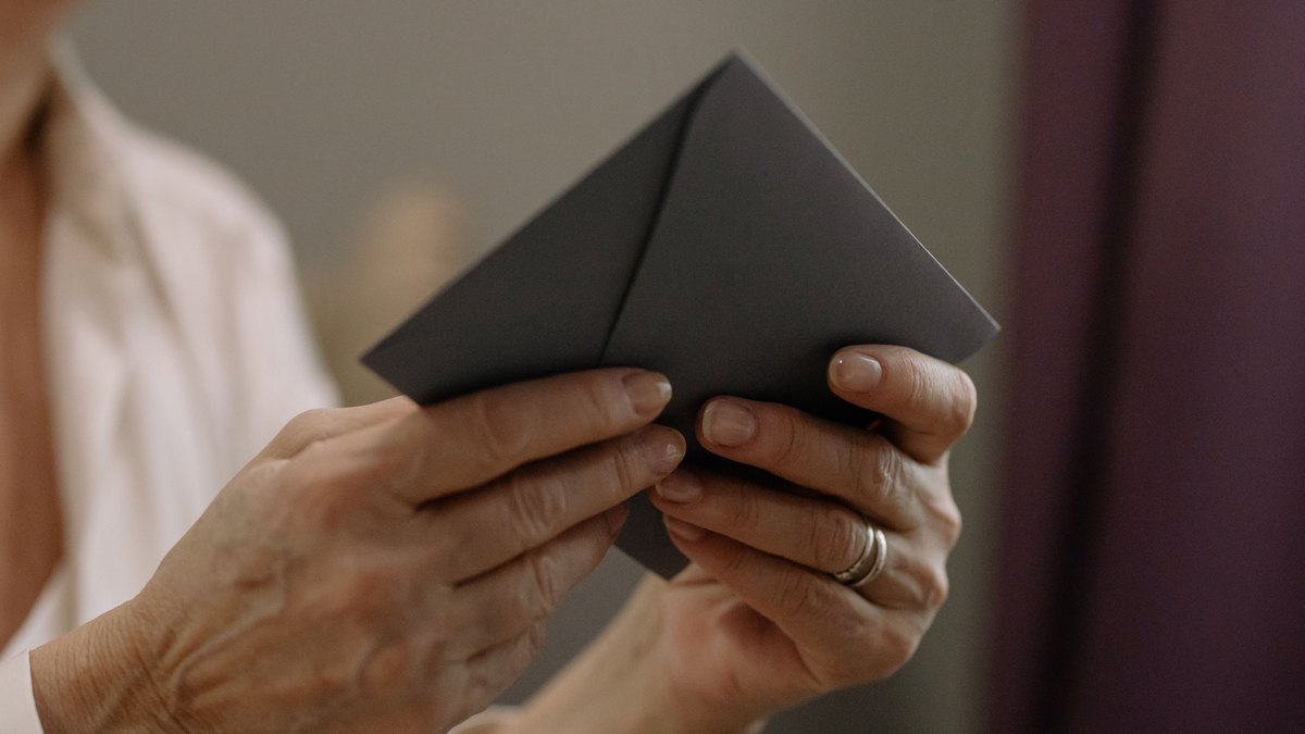 Two hands holding a sealed envelope, close up.